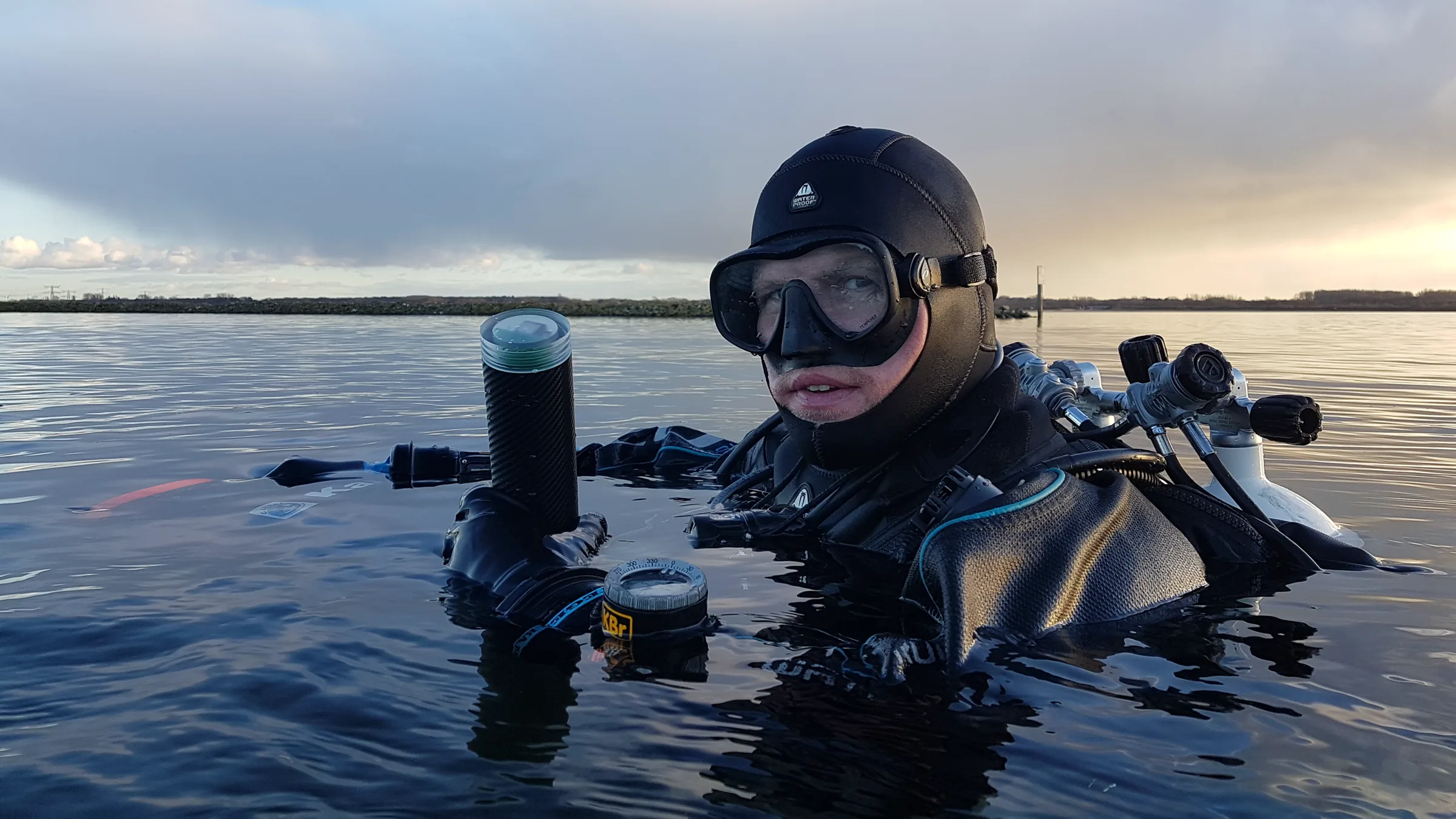 A diver at the surface at dusk with the Gramper GPS buoy beside him
